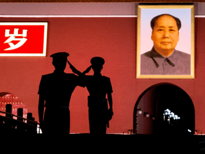 Chinese Paramilitary police officers salute each other as they stand guard below a portrai