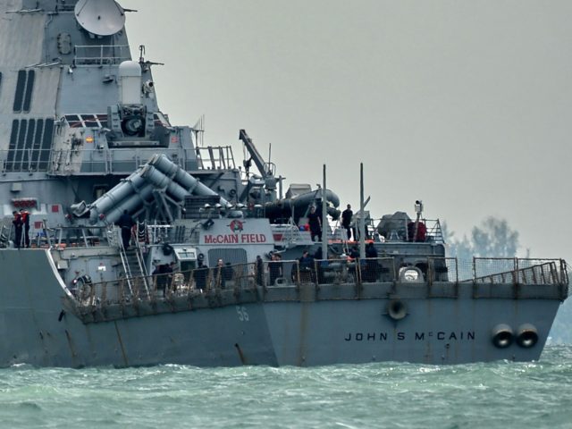 The guided-missile destroyer USS John S. McCain, with a hole on its portside after a collision with an oil tanker, makes its way to Changi naval base in Singapore on August 21, 2017. Ten US sailors were missing and five injured after their destroyer collided with a tanker east of …