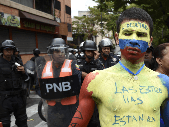 A man with his body painted in the Venezuelan national flag's colors, demonstrates in fron