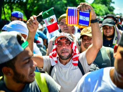 A migrant heading in a caravan to the US, holds Mexican, US and Honduran national flags on the road linking Ciudad Hidalgo and Tapachula, Chiapas state, Mexico, on October 21, 2018. - Thousands of Honduran migrants resumed their march toward the United States on Sunday from the southern Mexican city …