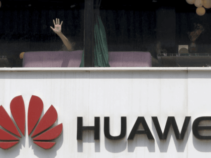 A man presses on the glass window near a logo for Huawei in Beijing on Thursday, May 16, 2