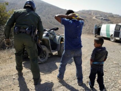 In this June 28, 2018, file photo, a Guatemalan father and son, who crossed the U.S.-Mexico border illegally, are apprehended by a U.S. Border Patrol agent in San Diego. California will introduce group trials on Monday, July 9, for people charged with entering the country illegally. Federal prosecutors in Arizona, …