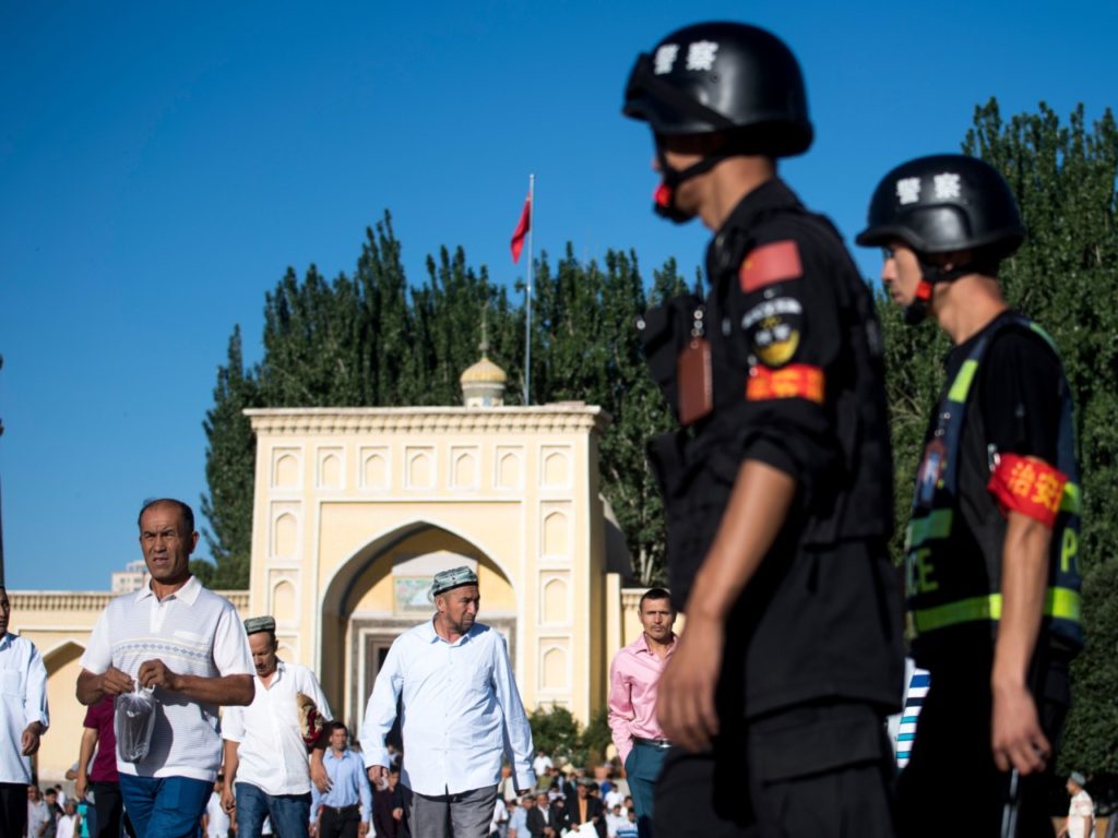 This picture taken on June 26, 2017 shows police patrolling as Muslims leave the Id Kah Mosque after the morning prayer on Eid al-Fitr in the old town of Kashgar in China's Xinjiang Uighur Autonomous Region. The increasingly strict curbs imposed on the mostly Muslim Uighur population have stifled life in the tense Xinjiang region, where beards are partially banned and no one is allowed to pray in public. Beijing says the restrictions and heavy police presence seek to control the spread of Islamic extremism and separatist movements, but analysts warn that Xinjiang is becoming an open air prison. / AFP PHOTO / Johannes EISELE / TO GO WITH China-religion-politics, FOCUS by Ben Dooley (Photo credit should read JOHANNES EISELE/AFP/Getty Images)