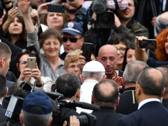 Pope Francis is surrounded by journalists and aides as he arrives to celebrate a Holy Mass