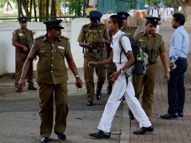 Sri Lankan police stand guard as school students return to classes as schools re-open acro