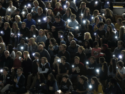 Attendees illuminate their mobile telephones during a community vigil to honor the victims