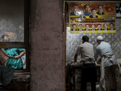 Uighur men in Kashgar make bread under a poster of Chinese leaders, including Mao Zedong and Xi Jinping, in 2017. Detainees are reportedly forced to chant patriotic songs about Xi in order to get food in detention camps.Kevin Frayer/Getty Images