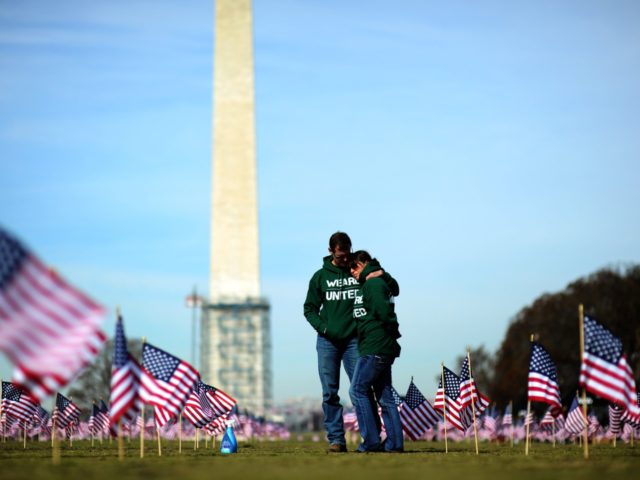 Iraq war veteran couple Colleen Ryan and Jeff Hensley of the US Navy comfort each other as they help set up 1,892 American flags on the National Mall in Washington, DC, on March 27, 2014. The Iraq and Afghanistan veterans installed the flags to represent the 1,892 veterans and service …