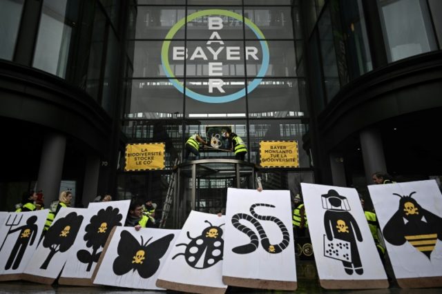 (FILES) In this file photo taken on March 14, 2019, activists stage a flash protest organised by the international movement Attac at the offices of Bayer - which recently acquired Monsanto - in La Garenne Colombes near the financial district of La Defense on the outskirts of Paris.Germany's Bayer apologised on May 12, 2019 after revelations in France that its subsidiary Monsanto had a PR agency collate lists of politicians, scientists and journalists and their views on pesticides and GM crops. Bayer admits Monsanto may have other 'watch lists'