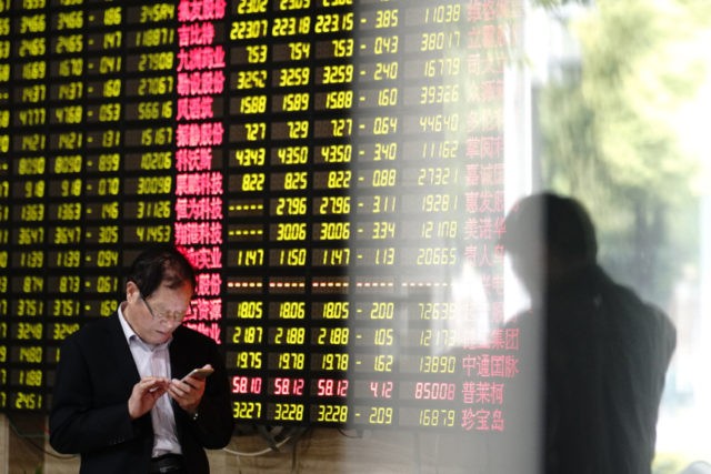 US Trump China Tariffs A man looks at his smartphone near a display showing stock prices at a brokerage house in Shanghai Monday, May 6, 2019. China's benchmark Shanghai Composite index dives on U.S. President Donald Trump threat of more China tariffs. At right is a reflection off a display board. (AP Photo) The Associated Press