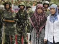 Two ethnic Uighur women pass Chinese paramilitary policemen standing guard outside the Grand Bazaar in the Uighur district of the city of Urumqi in China's Xinjiang region on July 14, 2009. A mosque was closed and many businesses were shuttered a day after police shot dead two Muslim Uighurs, as …