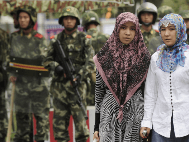 Two ethnic Uighur women pass Chinese paramilitary policemen standing guard outside the Gra