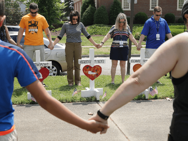 People hold hands and pray together at a makeshift memorial for the 12 victims of a mass s