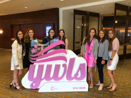 Event attendees pose for a photo in front of a YWLS sign. (Alana Mastrangelo/Breitbart News)