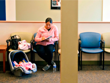 A woman fills out paperwork while waiting in a doctor's office.