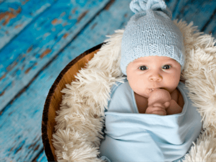 Little baby boy with knitted hat in a basket, happily smiling - stock photo Little baby boy with knitted hat in a basket, happily smiling and looking at camera, isolated studio shot