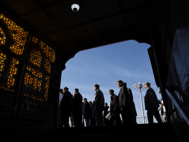 Uighur men make their way past a subway entrance after Eid al-Fitr prayers, marking the en