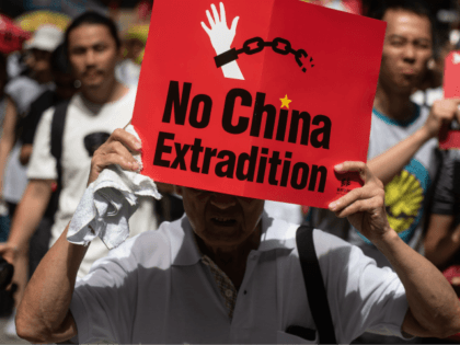TOPSHOT - A protester marches with a placard during a rally against a controversial extradition law proposal in Hong Kong on June 9, 2019. - Huge protest crowds thronged Hong Kong on June 9 as anger swells over plans to allow extraditions to China, a proposal that has sparked the …