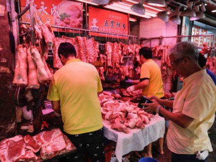 A customer waits as butchers prepare pork meat at a market in Hong Kong on May 11, 2019. - Hong Kong will cull 6,000 pigs after African swine fever was detected in an animal at a slaughterhouse close to the border with China, the first case of the disease in …