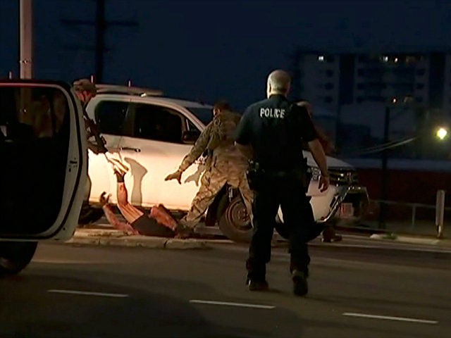 In this image made from video, police proceed to apprehend a suspect on the ground next to