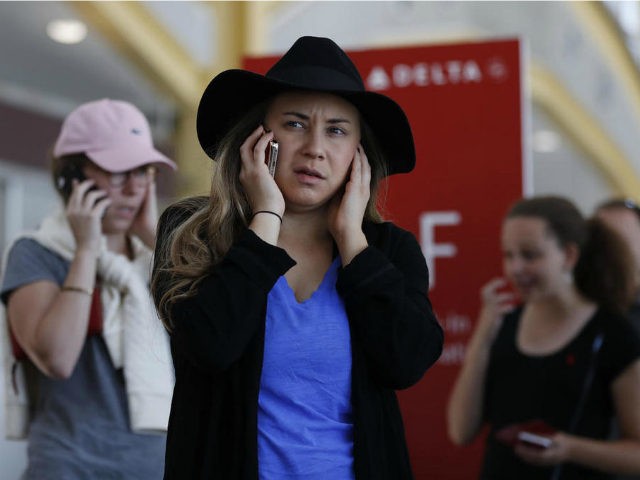 Jenna Raspanti and other travelers talk on their cell phones as they stand in line at the Delta ticketing counter at Washington's Ronald Reagan Washington National Airport, Monday, Aug. 8, 2016. Raspanti is trying to get to San Francisco after her Delta flight was delayed. Delta Air Lines delayed or …