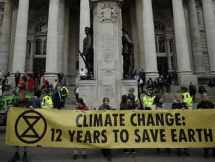 FILE - In this Thursday, April 25, 2019 file photo, Extinction Rebellion climate change protesters hold up a banner near the Bank of England, in the City of London. The environmental activist group Extinction Rebellion has postponed a plan to shut down London's Heathrow Airport with drones after it was …