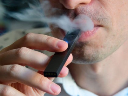 An illustration shows a man exhaling smoke from an electronic cigarette in Washington, DC on October 2, 2018. - In just three years, the electronic cigarette manufacturer Juul has swallowed the American market with its vaporettes in the shape of a USB key. Its success represents a public health dilemma …