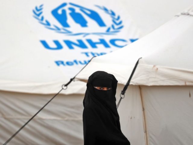 A fully veiled displaced Syrian youth stands at the Internally Displaced Persons (IDP) cam