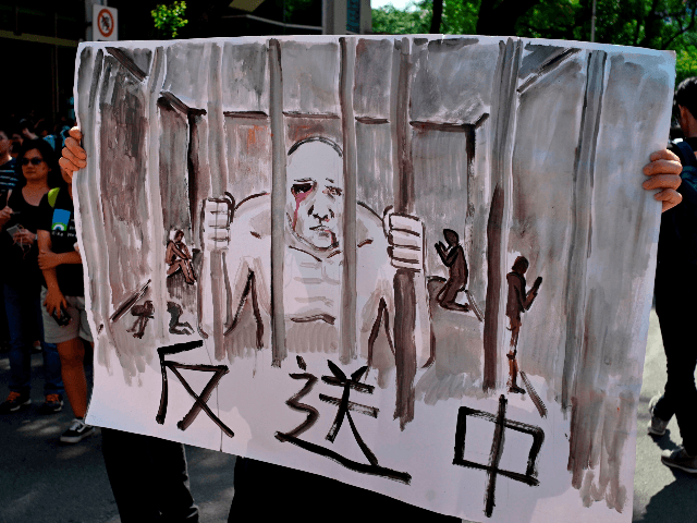 A protester displays a painting during a demonstration in Taipei on June 16, 2019, in supp