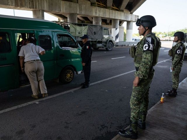 Members of the National Guard stand as an immigration officer check's passengers' documents at a checkpoint on June 18, 2019 on a highway in Tuxtla Chico, Mexico. The Mexican government launched a deployment of the National Guard seeking to control the flux of migrants crossing from Guatemala to Mexico, as …