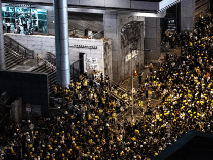 A group of police officers in riot gear (L) stand by at the police headquarters as protesters gather outside the building in Hong Kong on June 21, 2019. - Thousands of protesters converged on Hong Kong's police headquarters on June 21, demanding the resignation of the city's pro-Beijing leader and …