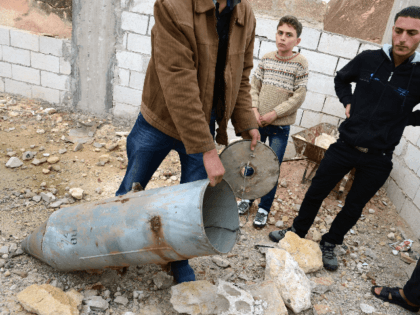 A Syrian man shows a cluster bomb, that releases or ejects smaller sub-munitions, in the northern Syrian town of Taftanaz, in the Idlib province, on November 9, 2012. Syrian President Bashar al-Assad said his future could only be decided at the ballot box and denied Syria was in a state …