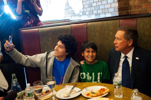 NEW YORK - MARCH 30: GOP Presidential Candidate John Kasich (right) poses with two children at Gino's Pizzeria and Restaurant on March 30, 2016 in the Queens borough of New York City. Kasich is one of three remaining GOP Presidential Candidates fighting for New York's 95 Republican delegates in the …