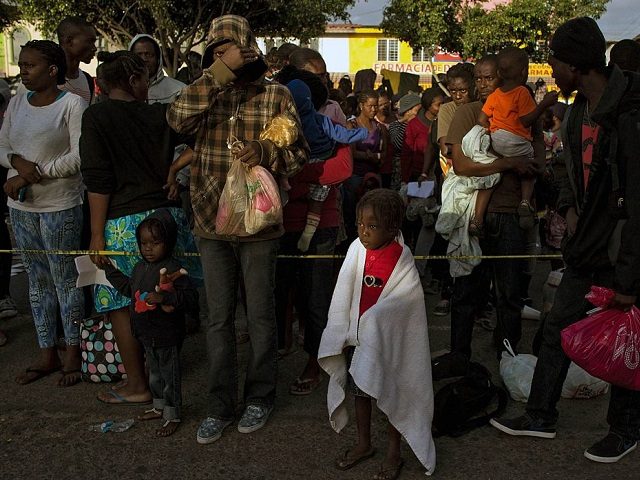 Haitian and African migrants seeking for asylum in the United States, line up outside a Me