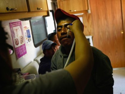 WELLINGTON, CO - SEPTEMBER 16: Migrant outreach worker Jessica Maciel takes the temperature of a migrant farm worker during a check-up in a mobile clinic on September 16, 2009 on a spinach farm near Wellington, Colorado. The Salud Family Health Centers sends the mobile clinic to farms across northeastern Colorado …
