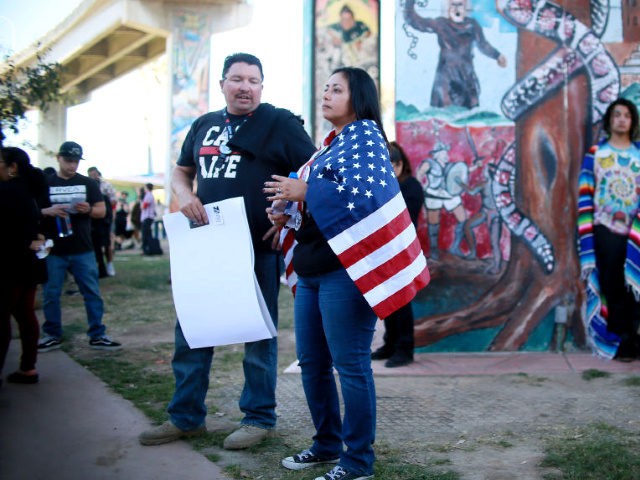 A Hispanic woman stands draped in the American flag opposite a "Patriot Picnic" demonstration at Chicano Park on February 3, 2018 in San Diego. / AFP PHOTO / SANDY HUFFAKER (Photo credit should read SANDY HUFFAKER/AFP/Getty Images)