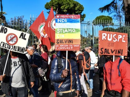 People, including employees of the country's social and reception centers and members of anti-racism associations, march during a demonstration against the government's social politics, its recent decree restricting the right to asylum, and against racism on November 10, 2018 in downtown Rome. - The placards read (From L) "No to …