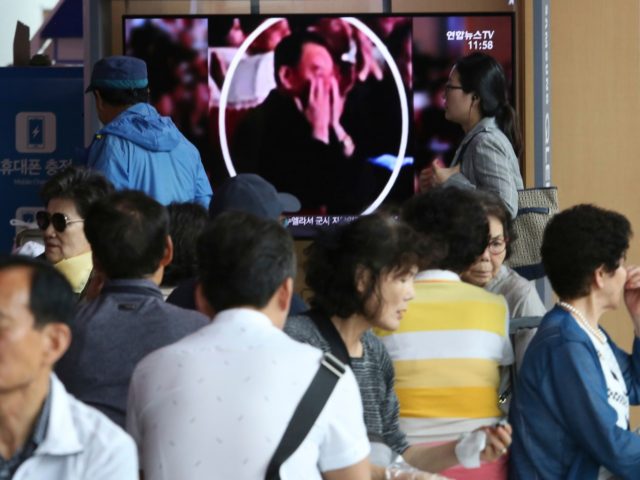 People watch a TV screen showing an image of senior North Korean official Kim Yong Chol in