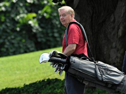 Sen. Lindsey Graham, R-S.C., carries his golf clubs as he walks down the driveway of the W