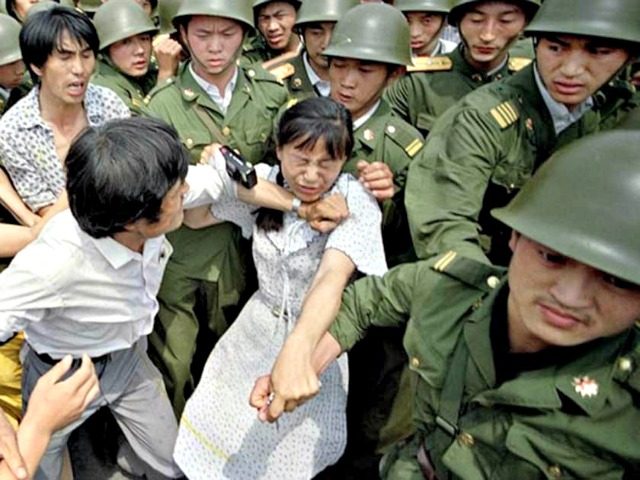 A woman is caught between civilians and soldiers, who were trying to remove her from an assembly near the Great Hall of the People in Beijing on June 3, 1989. (Jeff Widener / Associated Press)