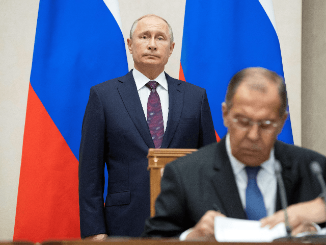 Russian Foreign Minister Sergei Lavrov (R) signs documents as Russian President Vladimir P
