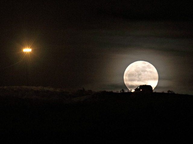 A full moon rises over the US-Mexico border as a border protection vehicle patrols the are