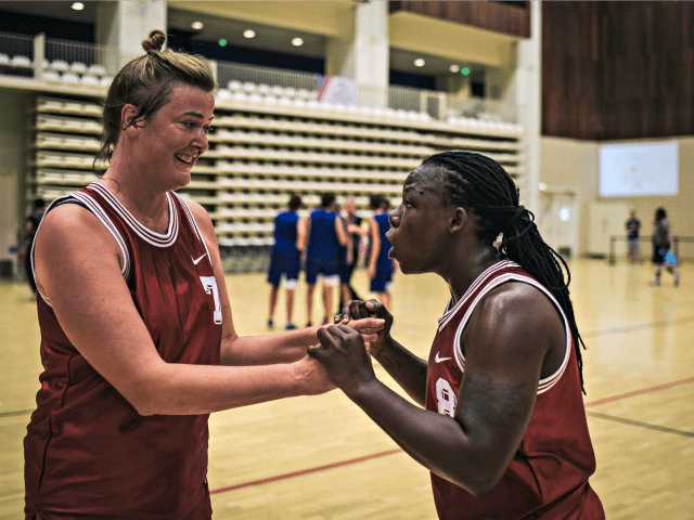 Ugandan transgender player Jay Mulucha (R) speaks with a teammate during the basketball co