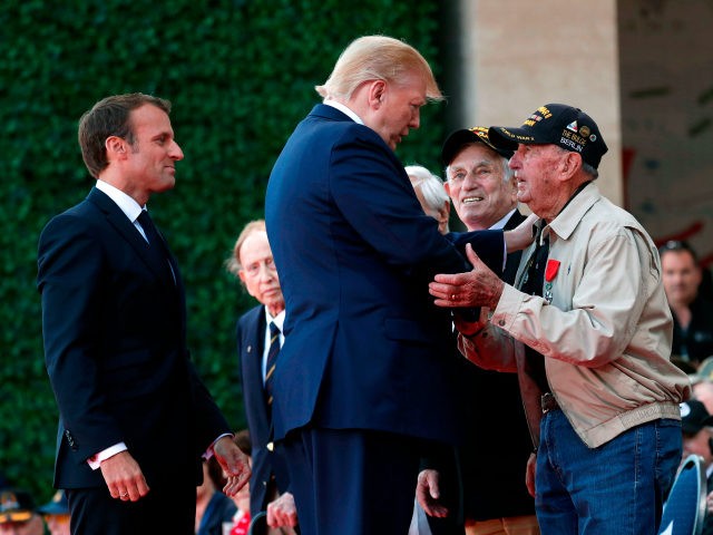 US President Donald Trump (C) and French President Emmanuel Macron (L) greet a US veteran during a French-US ceremony at the Normandy American Cemetery and Memorial in Colleville-sur-Mer, Normandy, northwestern France, on June 6, 2019, as part of D-Day commemorations marking the 75th anniversary of the World War II Allied …