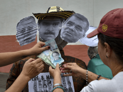 Opponents to the government place Bolivar banknotes on dummies depicting Venezuelan President Nicolas Maduro (C), Venezuelan Defense Minister Vladimir Padrino (R), and the former speaker of the Venezuelan National Assembly, Diosdado Cabello, as they prepare to burn them during the traditional "burning of Judas" on Easter Day at Chacao neighborhood, …