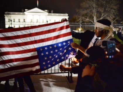 Protesters try unsuccessfully to burn an upside down US flag during a protest outside the White House in Washington, DC on November 25, 2014, one day after a grand jury decision not to prosecute a white police officer for the killing of an unarmed black teen in Ferguson, Missouri. AFP …