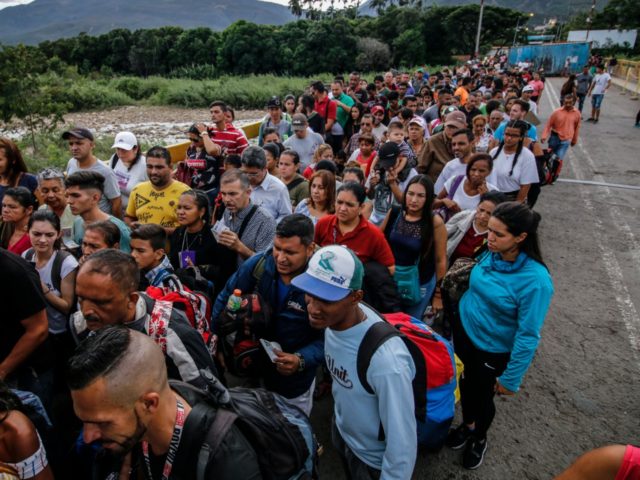 TOPSHOT - People queue to cross the Simon Bolivar international bridge from San Antonio de