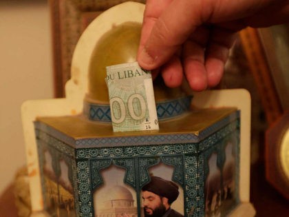A man drops a bank note in a donation box in the form of Jerusalem's Dome of the Rock mosque, and bearing a portrait the head of Lebanon's militant Shiite movement Hezbollah, in a southern suburb of the capital Beirut on June 3, 2019. - The militant Shiite organisation, a …