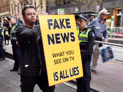 A man holds up a 'Fake News' placard as members of the Australian Liberty Alliance (ALA) a