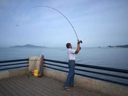A man casts his fishing rod in Weihai, east China's Shandong province on July 22, 2014. Tens of thousands of domestic tourists visit the coastal city during summer. AFP PHOTO / WANG ZHAO (Photo credit should read WANG ZHAO/AFP/Getty Images)